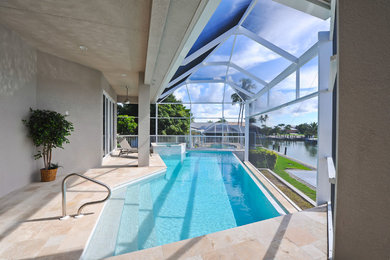 Diseño de piscina con fuente infinita actual a medida en patio trasero con suelo de baldosas