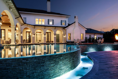 Inspiration for an expansive classic back custom shaped infinity hot tub with natural stone paving.