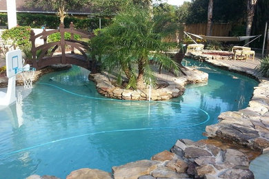 Modelo de piscina con fuente natural grande redondeada en patio trasero con adoquines de piedra natural