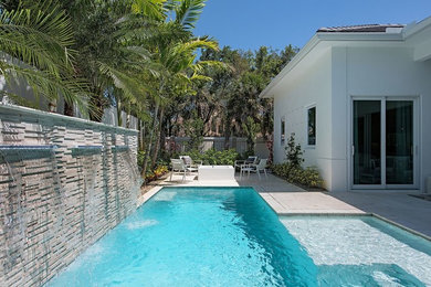 Inspiration for a large contemporary backyard stone and rectangular lap pool fountain remodel in Miami