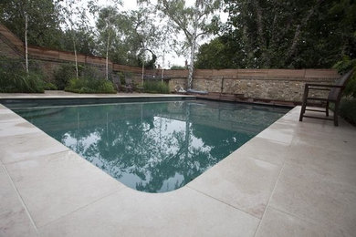 Ejemplo de piscina minimalista con adoquines de piedra natural