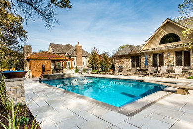Modelo de casa de la piscina y piscina actual rectangular en patio trasero con adoquines de piedra natural