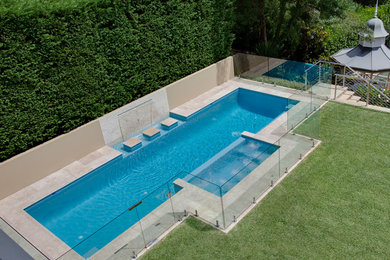 Пример оригинального дизайна: большой спортивный бассейн произвольной формы на заднем дворе в стиле модернизм с джакузи и покрытием из бетонных плит