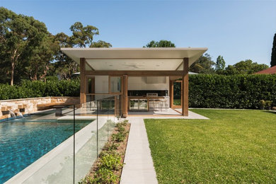 Diseño de piscina rectangular en patio trasero con adoquines de piedra natural