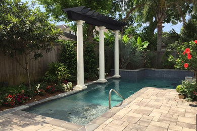 Imagen de piscina con fuente alargada clásica de tamaño medio rectangular en patio trasero con adoquines de piedra natural