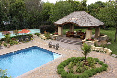 Inredning av en klassisk mellanstor rektangulär pool på baksidan av huset, med poolhus och naturstensplattor
