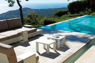Modelo de piscina infinita contemporánea grande rectangular en patio trasero con entablado