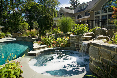 Imagen de piscina con fuente tradicional de tamaño medio a medida en patio trasero con adoquines de piedra natural