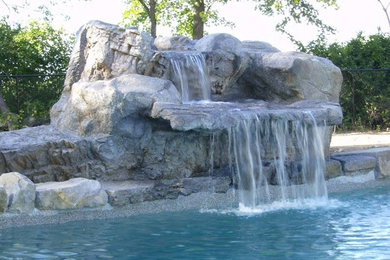 Ejemplo de piscina con fuente alargada rústica grande en patio trasero con adoquines de piedra natural