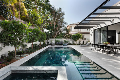 Esempio di una piscina a sfioro infinito moderna di medie dimensioni con una vasca idromassaggio e pavimentazioni in pietra naturale