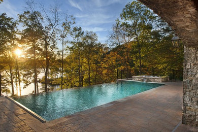 Aménagement d'une piscine à débordement et arrière exotique de taille moyenne et rectangle avec un bain bouillonnant et des pavés en béton.