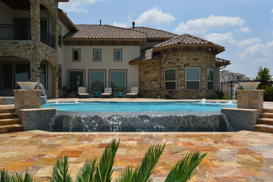Ejemplo de piscina con fuente infinita minimalista grande a medida en patio trasero con adoquines de piedra natural