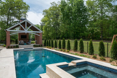 Стильный дизайн: большой спортивный, прямоугольный бассейн на заднем дворе в классическом стиле с джакузи и покрытием из каменной брусчатки - последний тренд