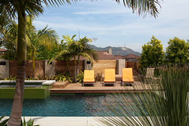 Imagen de piscina exótica grande rectangular en patio trasero con losas de hormigón