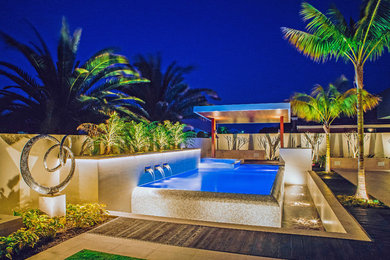 Modelo de piscina infinita exótica de tamaño medio tipo riñón en patio lateral con suelo de baldosas