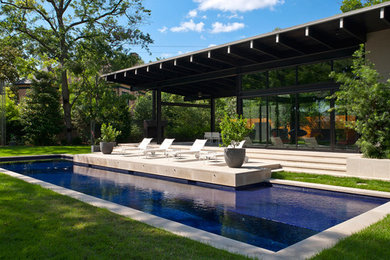 This is an example of a medium sized contemporary back rectangular swimming pool in Houston with a pool house and concrete paving.