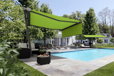 Modelo de piscina alargada contemporánea grande rectangular en patio trasero con adoquines de hormigón