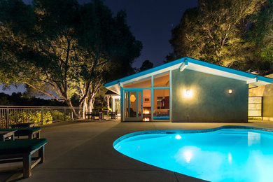 Diseño de piscina alargada contemporánea grande a medida en patio trasero con losas de hormigón