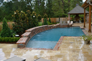Diseño de piscina tradicional a medida en patio trasero con adoquines de piedra natural