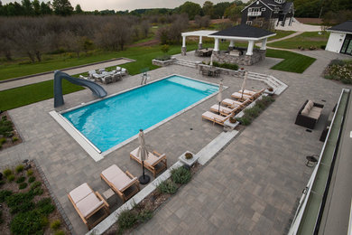 Example of a large trendy backyard concrete paver and rectangular lap pool house design in Other