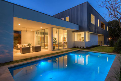 Medium sized contemporary back rectangular lengths swimming pool in Austin with a pool house and concrete slabs.