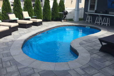 Ejemplo de piscina alargada tradicional renovada de tamaño medio tipo riñón en patio trasero con adoquines de hormigón