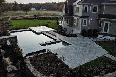Diseño de piscinas y jacuzzis infinitos eclécticos grandes a medida en patio trasero con adoquines de piedra natural