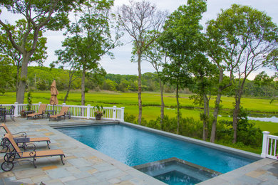Mid-sized elegant backyard stone and l-shaped lap hot tub photo in Other