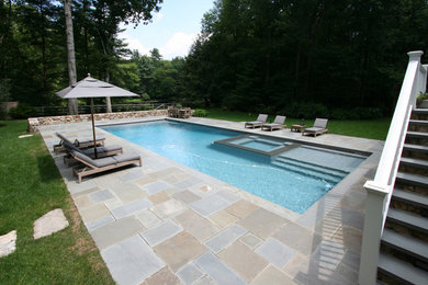 Exemple d'une grande piscine arrière rectangle avec un bain bouillonnant.