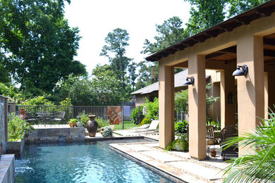 Foto de piscina con fuente tropical rectangular en patio trasero con adoquines de piedra natural