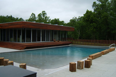 Modelo de piscina alargada actual grande rectangular en patio trasero con adoquines de hormigón