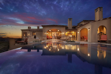 Hot tub - large mediterranean backyard stone and rectangular infinity hot tub idea in Phoenix