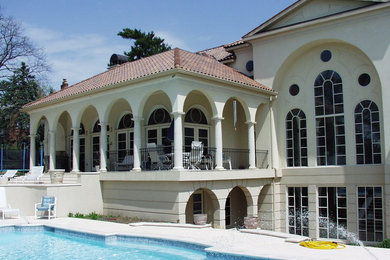 Diseño de piscina mediterránea grande a medida en patio trasero con adoquines de piedra natural