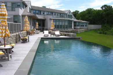 Immagine di una grande piscina a sfioro infinito moderna rettangolare dietro casa con lastre di cemento