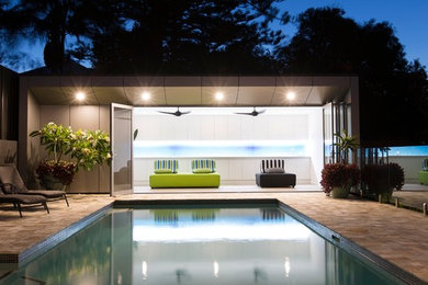 Стильный дизайн: спортивный, прямоугольный бассейн среднего размера на заднем дворе в современном стиле с домиком у бассейна и покрытием из плитки - последний тренд