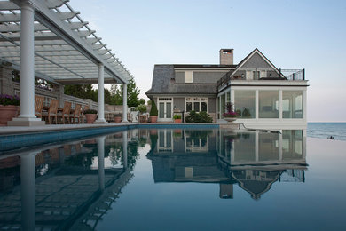 Ejemplo de piscina con fuente infinita clásica grande rectangular en patio lateral con adoquines de hormigón