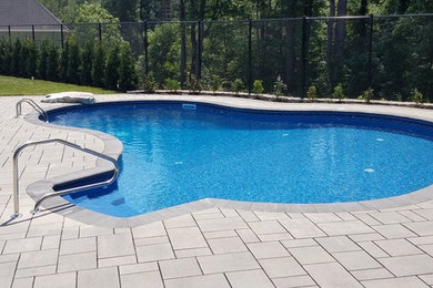 Example of a large backyard concrete paver and custom-shaped natural pool design in Boston
