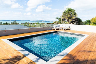Modelo de piscina elevada costera grande rectangular en patio trasero con entablado