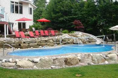 Diseño de piscina con tobogán tradicional grande a medida en patio trasero con adoquines de piedra natural