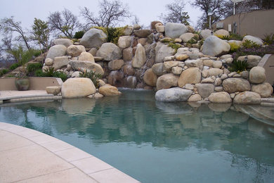 Pool fountain - large backyard concrete paver and custom-shaped pool fountain idea in Sacramento