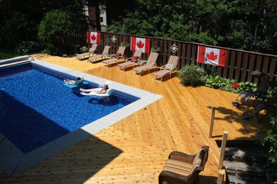 Diseño de piscina natural de tamaño medio rectangular en patio trasero con entablado