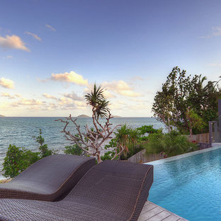 Ispirazione per una piscina a sfioro infinito tropicale rotonda dietro casa con pedane