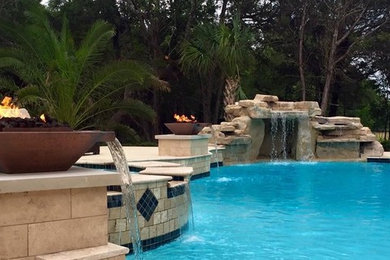 Ejemplo de piscina con fuente natural actual grande tipo riñón en patio trasero con adoquines de piedra natural