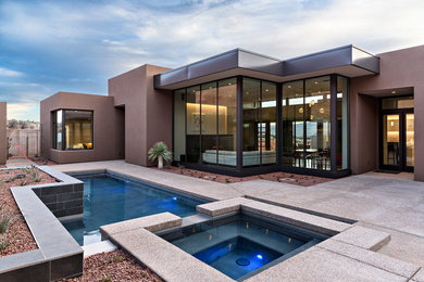 Ejemplo de piscinas y jacuzzis alargados de estilo americano de tamaño medio a medida en patio trasero con adoquines de hormigón
