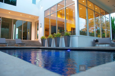 Ejemplo de piscina con fuente infinita moderna de tamaño medio rectangular en patio trasero con losas de hormigón