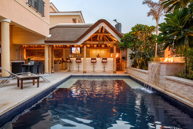 Ejemplo de piscina tropical rectangular con suelo de baldosas