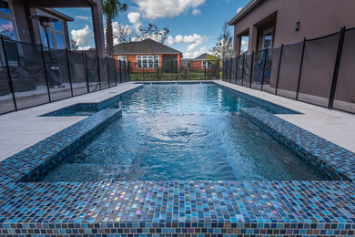 Design ideas for a medium sized contemporary back custom shaped swimming pool in Orlando with a water feature.