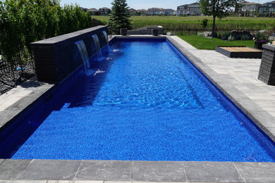 Foto de piscina minimalista de tamaño medio rectangular en patio trasero con adoquines de ladrillo