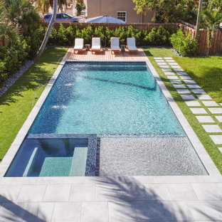 Esempio di una piscina monocorsia moderna rettangolare di medie dimensioni e dietro casa con una vasca idromassaggio e pedane