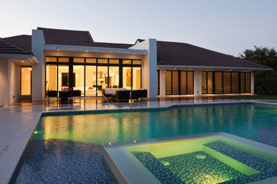 Example of a large trendy backyard rectangular infinity pool fountain design in Miami